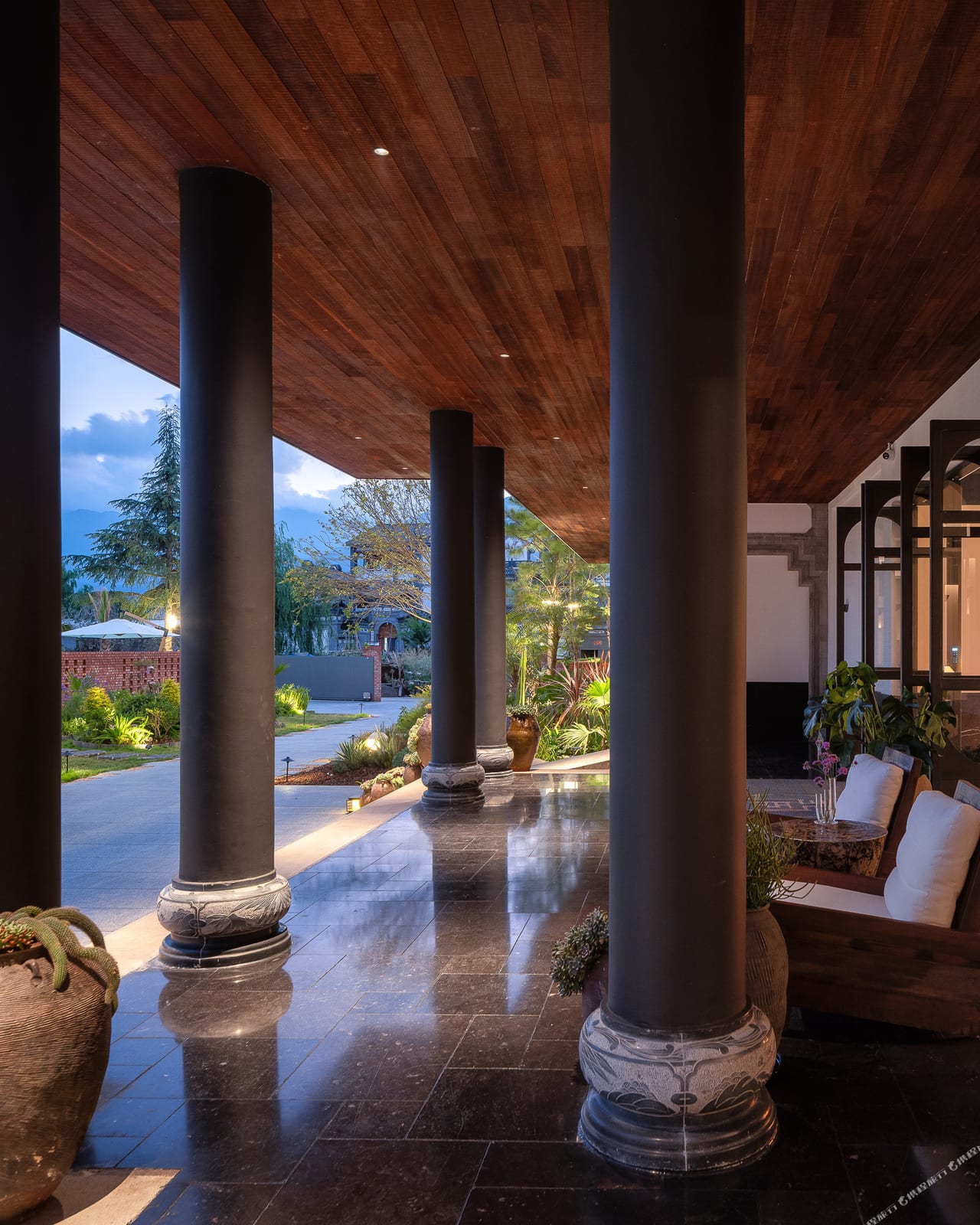 Kasion Erhai — the stone colonnade terrace beneath the timber eaves, looking onto the garden