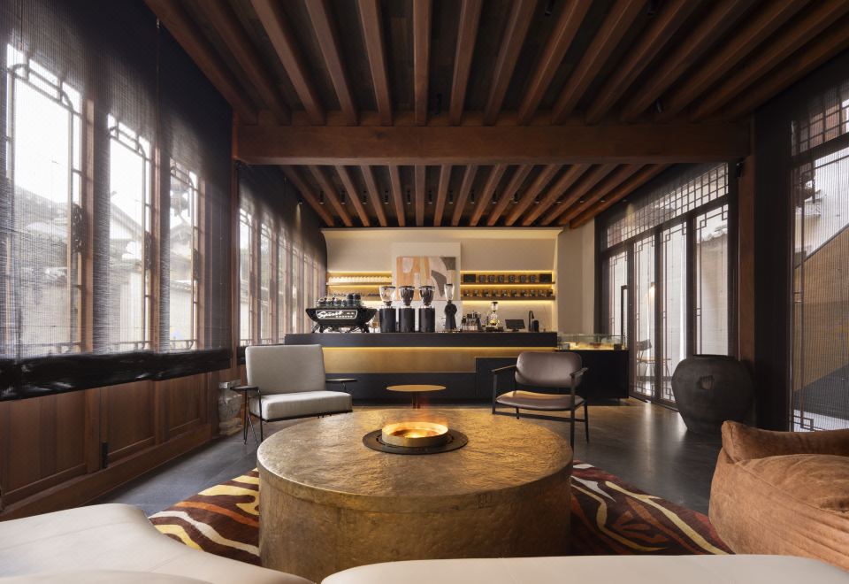 Kogongdi — coffee-bar lounge with deep wood beams, leather lounge chairs and a sunken brass fire pit