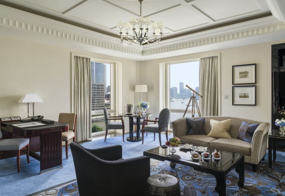 The Peninsula Shanghai (上海半岛酒店) — a suite living room with a brass telescope at the window over the Huangpu and the Pudong skyline
