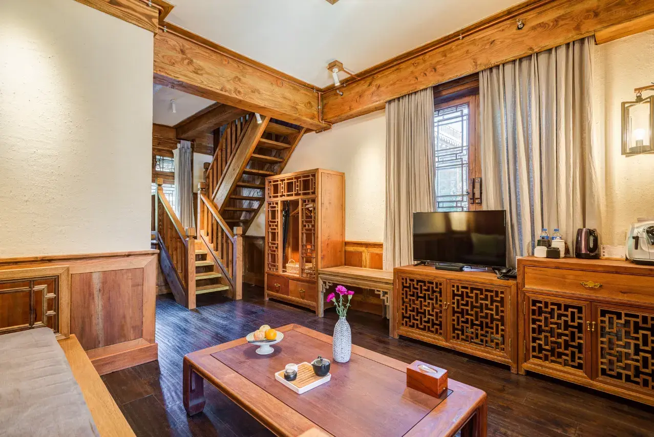 Suite living room with timber staircase, carved lattice cabinets and a low tea table with flowers.