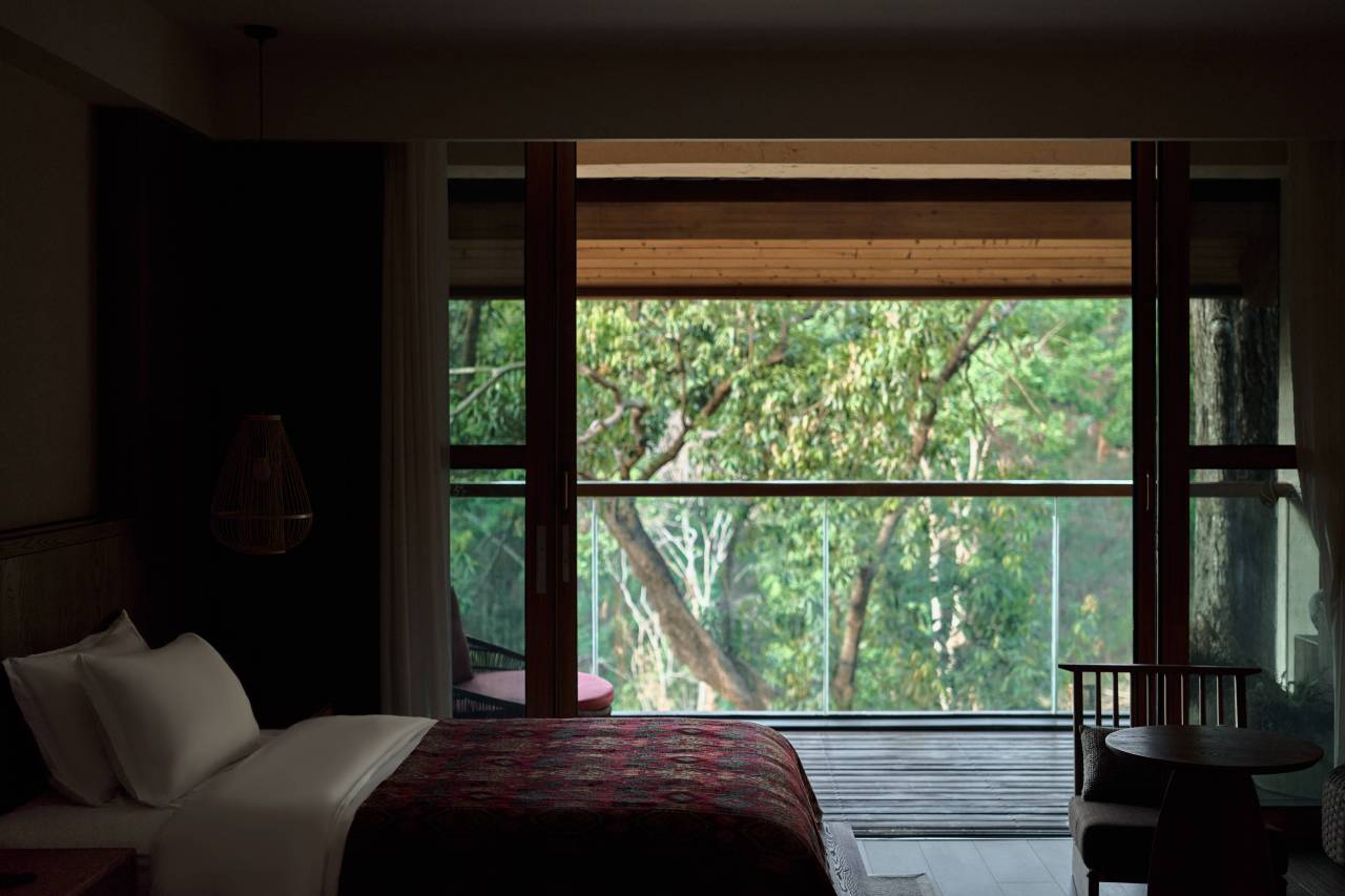 Vipaxana — guest room with ikat throw and full-height windows onto the tea forest