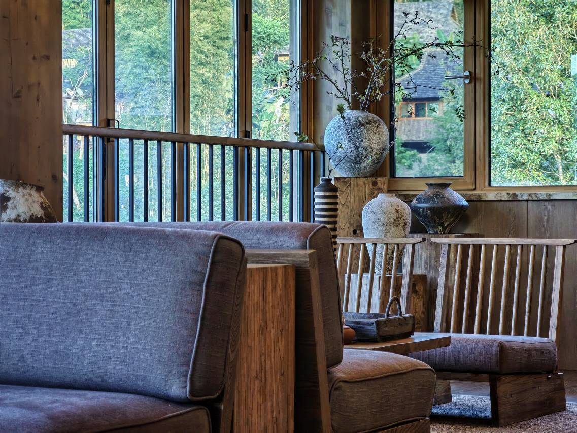Vipaxana — reading lounge with weathered stoneware and floor-to-ceiling forest windows