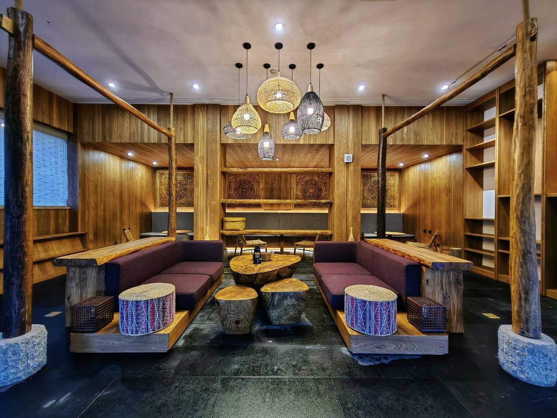 Vipaxana — Bulang-styled lounge with woven pendant lamps, log tables and painted panels