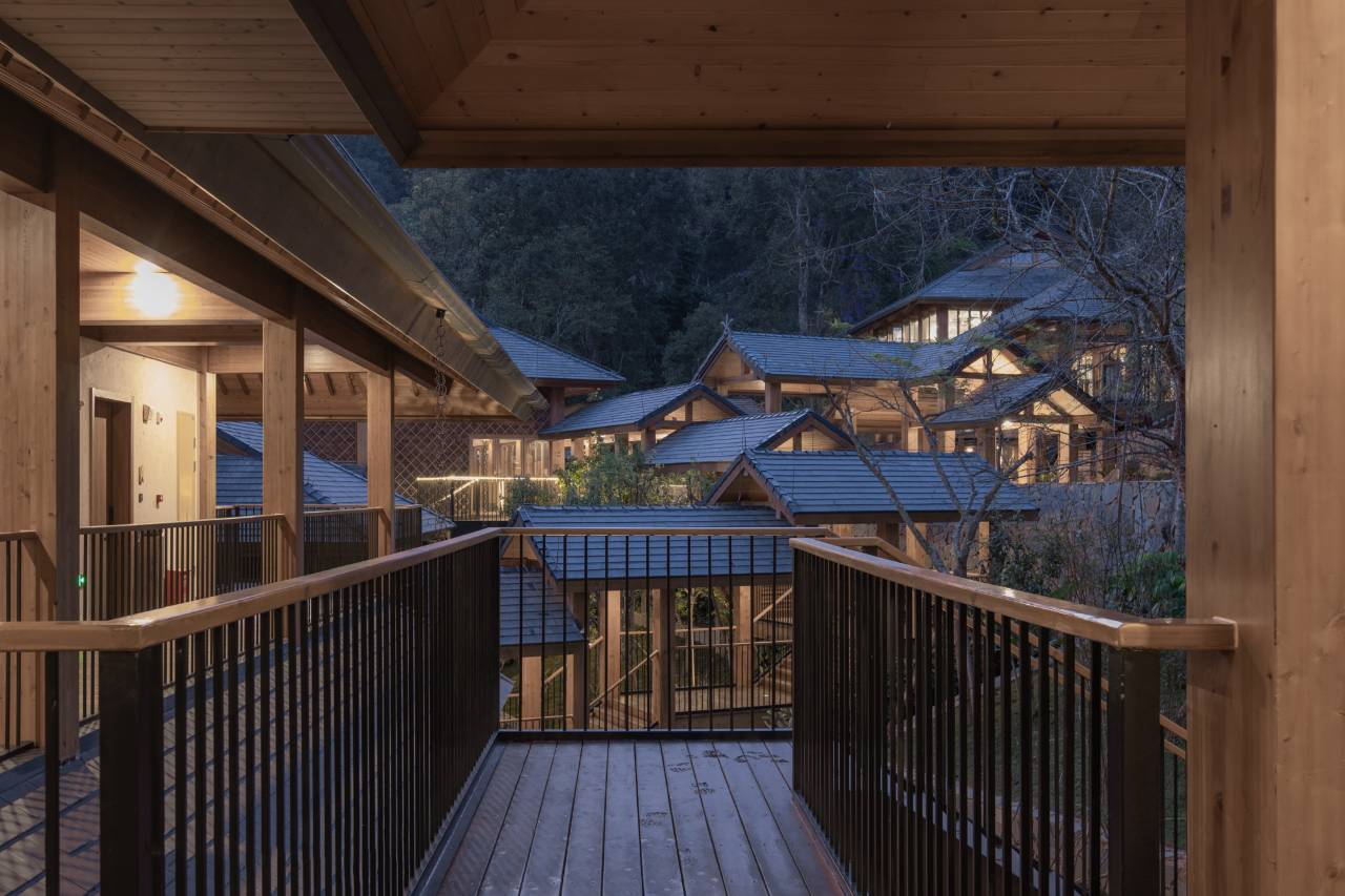 Vipaxana — timber walkway among the tiled pitched roofs at dusk, Jingmai Mountain