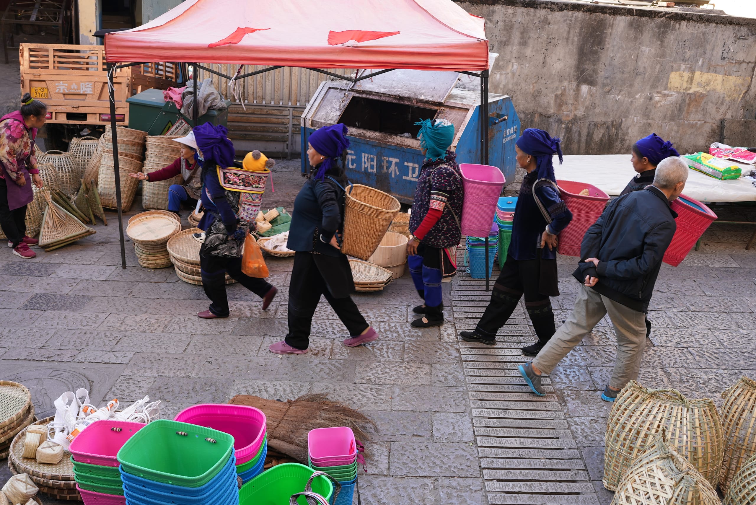 Hani women carrying baskets through a market street