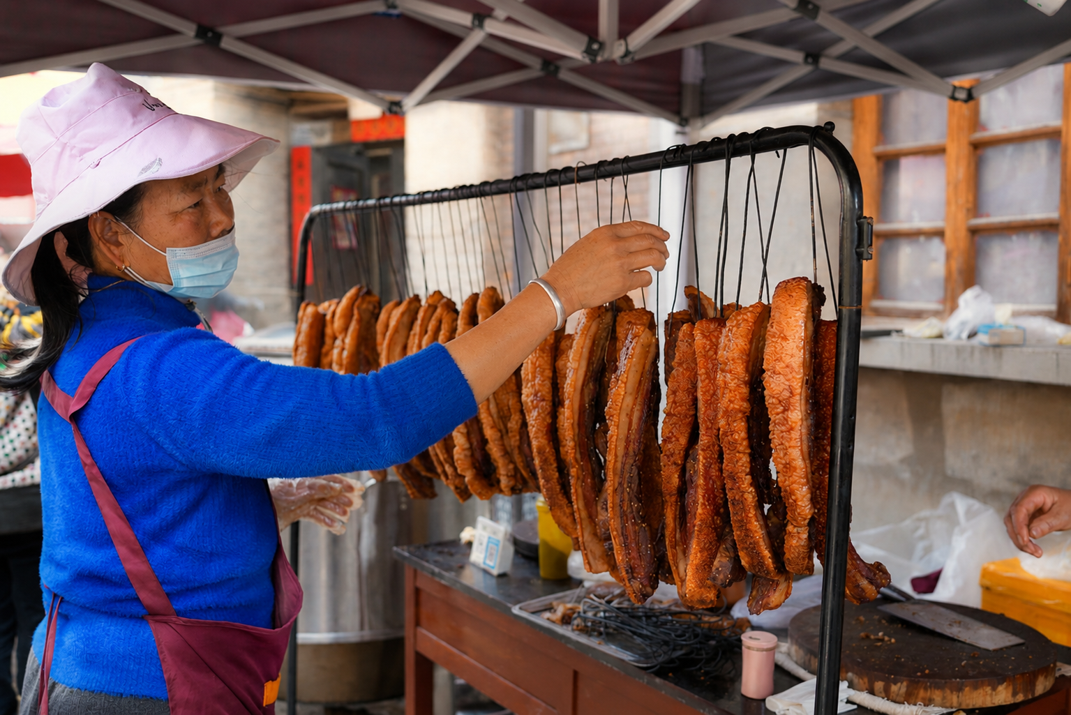 A local vendor hanging cured pork at a Yunnan market