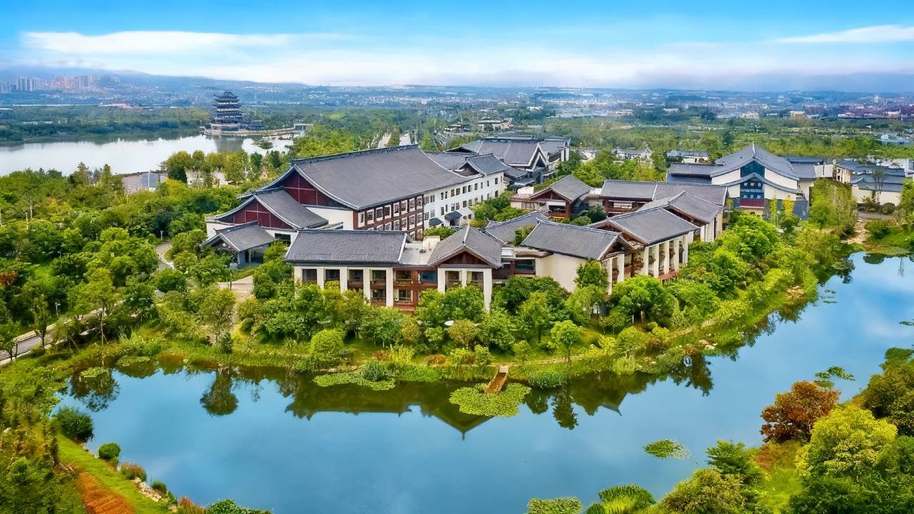 Guanfang Garden Hotel — grey-tiled wings and ponds seen from above, the Qinghuahai wetlands beyond